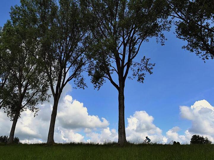 Eine Frau fährt auf ihrem Fahrrad vor dem teilweise mit Wolken überzogenen Himmel. Foto: Karl-Josef Hildenbrand/dpa
