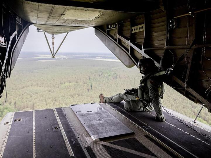 Ein Besatzungsmitglied der Lufttransportgruppe sitzt bei einem Löschflug der Luftwaffe über dem Waldbrandgebiet bei Jüterbog im CH53 Hubschrauber an der Heckklappe.