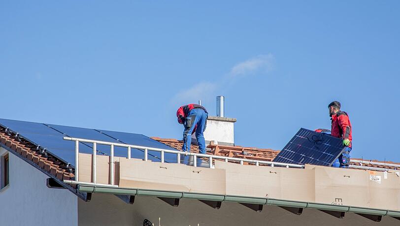 Bauarbeiter montieren auf einem Privathaus Solaranlagen. Nach dem Willen der Stadt sollen auch städtische Gebäude mehr Photovoltaik bekommen.
