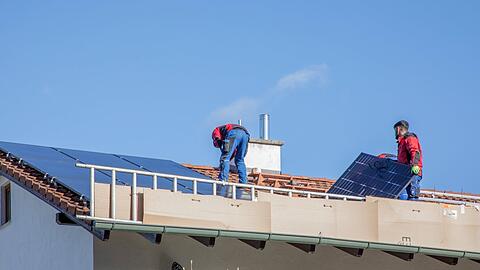 Bauarbeiter montieren auf einem Privathaus Solaranlagen. Nach dem Willen der Stadt sollen auch städtische Gebäude mehr Photovoltaik bekommen.