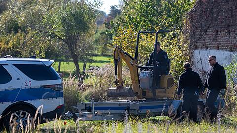 Polizisten untersuchen mit einem Bagger ein Grundstück in Herzberg (Landkreis Oder-Spree).