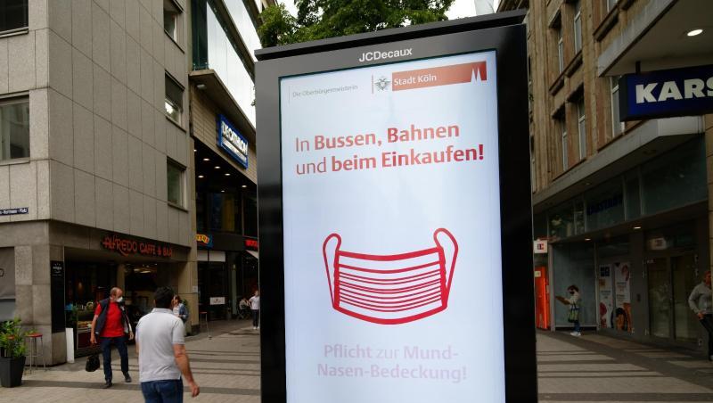 Ein Werbebildschirm weist in der Kölner Innenstadt auf die Maskenpflicht in Geschäften und im Nahverkehr hin. Ein Werbebildschirm weist in der Kölner Innenstadt auf die Maskenpflicht in Geschäften und im Nahverkehr hin.