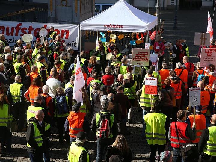 Demonstranten in bunten Westen stehen vor dem Düsseldorfer Rathaus.