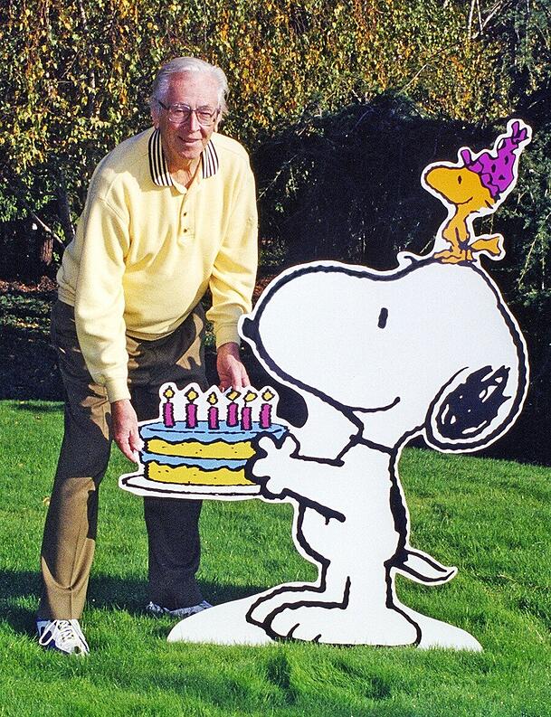 Charles M. Schulz Schöpfer der berühmten Peanuts-Figuren, steht neben Aufstellern, die Hund Snoopy und den kleinen gelben Vogel Woodstock darstellen. Charles M. Schulz neben dem Hund Snoopy und dem Vogel Woodstock.
