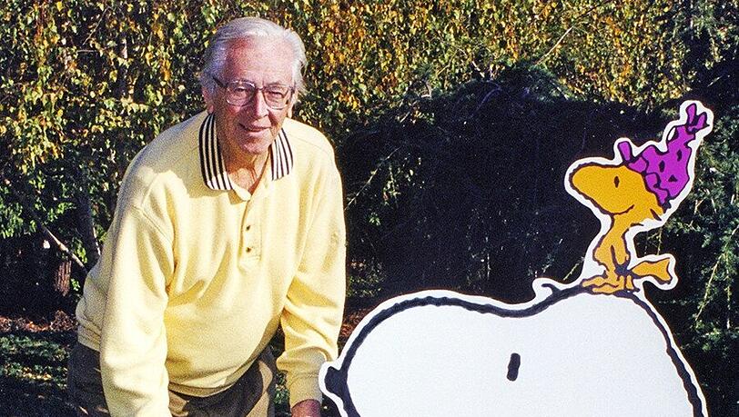 Charles M. Schulz Schöpfer der berühmten Peanuts-Figuren, steht neben Aufstellern, die Hund Snoopy und den kleinen gelben Vogel Woodstock darstellen. Charles M. Schulz neben dem Hund Snoopy und dem Vogel Woodstock.