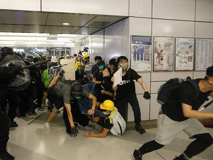 Eine Spezialeinheit der Polizei greift Demonstranten mit Schlagstöcken an, die sich weigern einen Bahnhof zu verlassen.