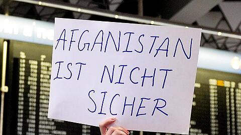 Eine Demonstrantin hält ein Plakat mit der Aufschrift "Afghanistan ist nicht sicher" in die Höhe. Foto: Susann Prautsch/Archivbild