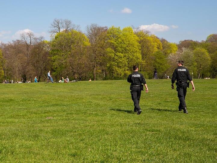 Zwei Polizisten gehen durch den Englischen Garten in München.