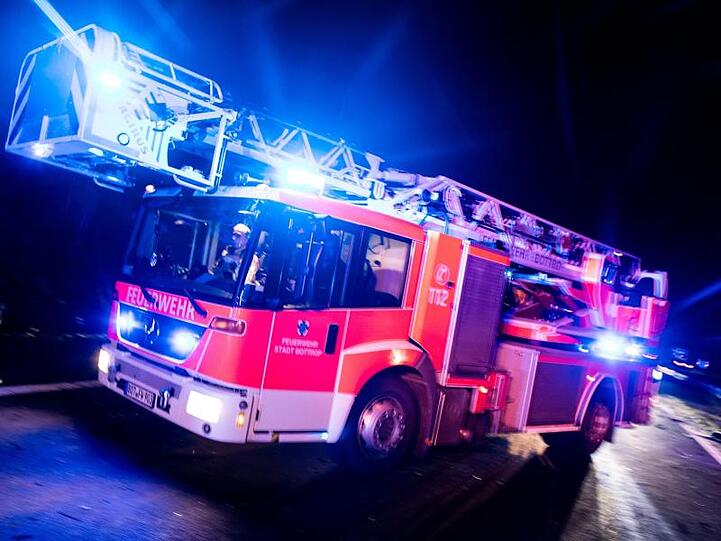 Ein Drehleiterwagen der Feuerwehr fährt mit Blaulicht an einer Unfallstelle vorbei. Foto: Marcel Kusch/dpa/Illustration
