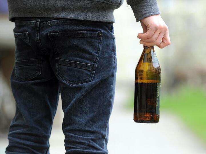Ein Jugendlicher hält eine geöffnete Bierflasche in der Hand. Foto: picture alliance / dpa/Archivbild