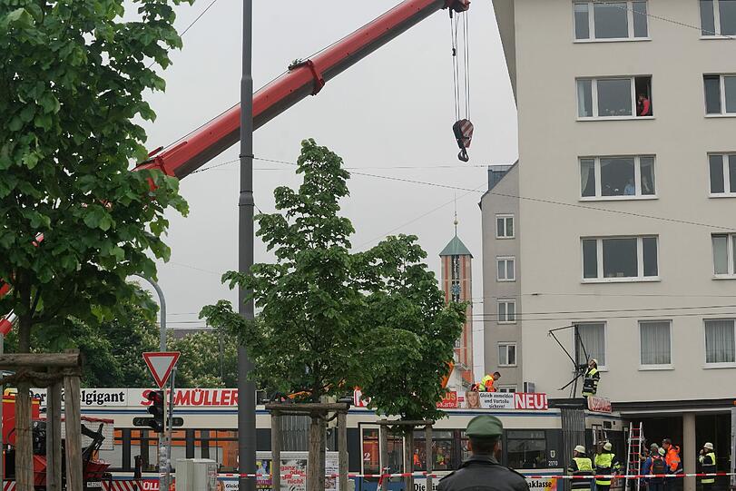 Die Feuerwehr ist mit einem Kran angerückt und will die eingeklemmte Tram befreien und wieder zurück in die Schiene heben.