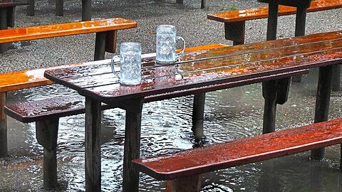 Die Maßkrüge sind voll, doch nicht mit Bier: Der Regen füllt zwar die Gläser wieder auf, aber nicht die Kassen der Biergarten-Wirte. Sie leiden unter dem nassen Wetter. Nur selten setzten sich Hartgesottene auch mit Regenjacke in den Biergarten.