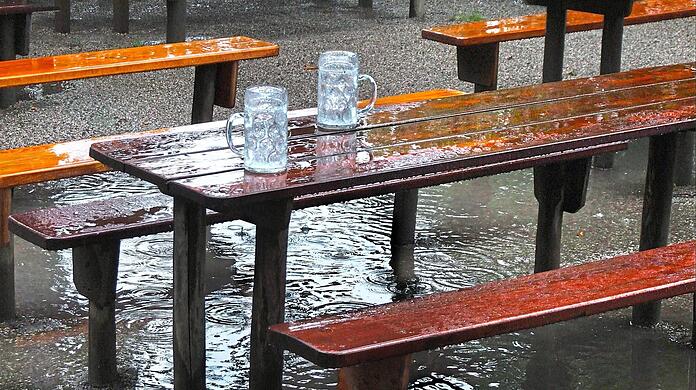 Die Maßkrüge sind voll, doch nicht mit Bier: Der Regen füllt zwar die Gläser wieder auf, aber nicht die Kassen der Biergarten-Wirte. Sie leiden unter dem nassen Wetter. Nur selten setzten sich Hartgesottene auch mit Regenjacke in den Biergarten.