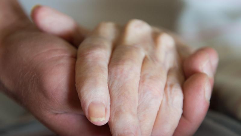Ein Altenpfleger hält in einem Pflegeheim die Hand einer Frau. Ein Altenpfleger hält in einem Pflegeheim die Hand einer Frau.