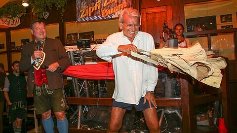 Abschiedswinken: Manfred Schauer (rechts, neben &bdquo;Auktionator&ldquo; Josef Schmid) trennt sich für den guten Zweck von seiner Wiesn-Hose.
