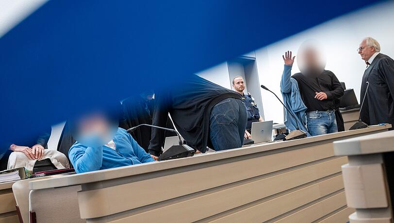 Angeklagte nehmen vor der Urteilsverkündung auf der Anklagebank Platz.
