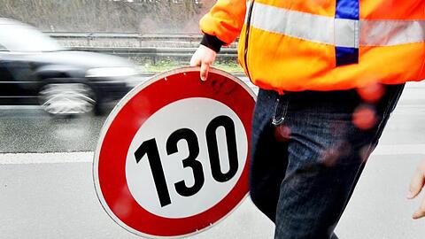 Ein Mitarbeiter der Autobahnmeisterei trägt ein Schild zur Höchstgeschwindigkeit von 130 Stundenkilometern. Foto: Marius Becker/dpa
