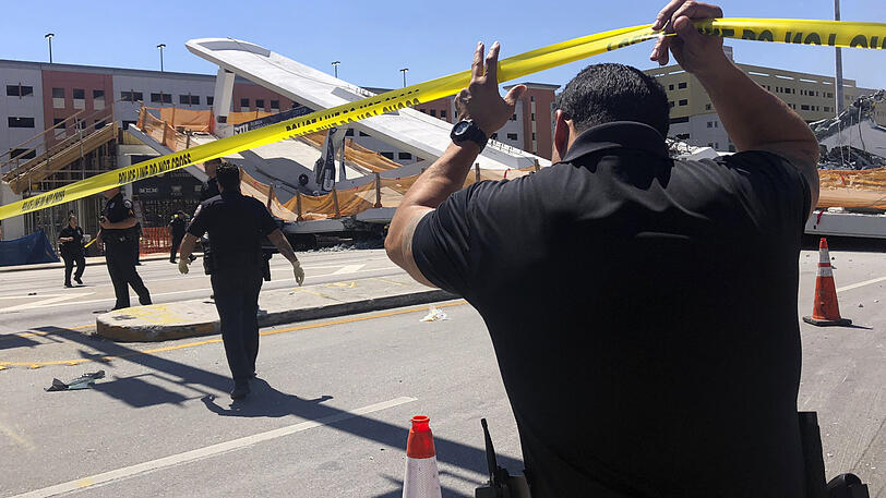 Rettungskräfte helfen an der Unfallstelle. Beim Einsturz einer neuen Fußgängerbrücke in der US-Metropole Miami sind mehrere Menschen getötet worden.