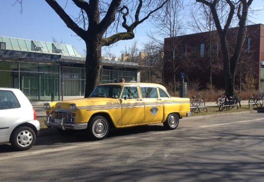 Das Taxi steht in der Alfonsstraße, gegenüber vom Sportplatz der Schule.