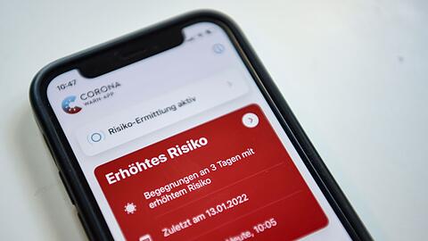 Auf einem Smartphone zeigt die geöffnete Corona-App ein erhöhtes Risiko an.