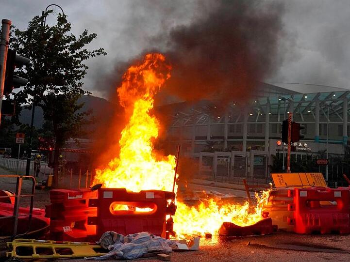 Von prodemokratischen Demonstranten vor dem Flughafen errichtete Barrikaden stehen in Flammen.