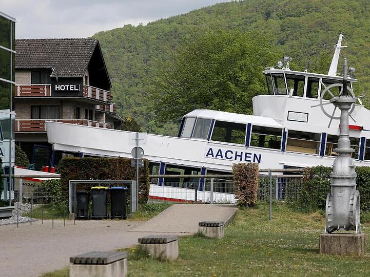Das Fahrgastschiff "Aachen" liegt am Ufer des Rursees vor einem Hotel auf dem Trockenen.