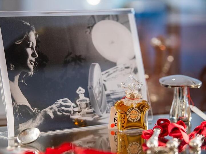 Ein Parfumflacon steht in einer Vitrine vor einem Foto von Romy Schneider. Rund 50 Gegenstände aus dem Besitz von Rosemarie Albach (Romy Schneider) werden im Auktionshaus Ruef versteigert.