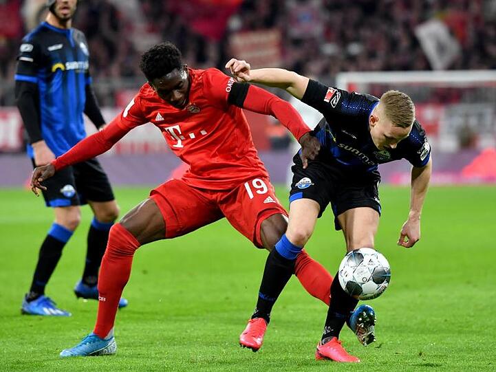 Alphonso Davies (l.) vom FC Bayern München und Kai Pröger von Paderborn kämpfen um den Ball. Foto: Peter Kneffel/dpa