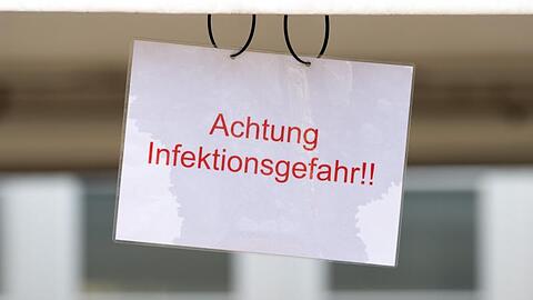 Ein Schild mit der Aufschrift "Achtung Infektionsgefahr!" an einem Johanniter-Zelt in Brandenburg.