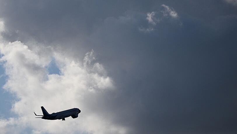 Ein Flugzeug fliegt nach seinem Sart am Flughafen München auf dunkle Wolke zu. (Symbolbild)