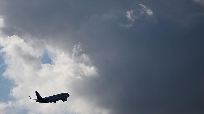 Ein Flugzeug fliegt nach seinem Sart am Flughafen München auf dunkle Wolke zu. (Symbolbild)