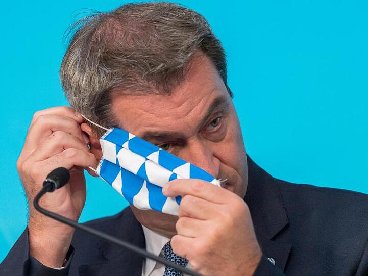 Markus Söder (CSU) setzt sich seine Mundschutzmaske auf. Foto: Peter Kneffel/dpa/Archivbild
