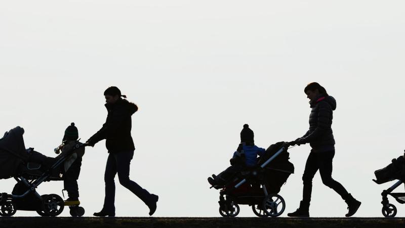 Drei Mütter schieben ihre Kinderwagen eine Landstraße entlang. Drei Mütter schieben ihre Kinderwagen eine Landstraße entlang.