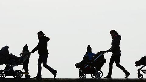 Drei Mütter schieben ihre Kinderwagen eine Landstraße entlang.