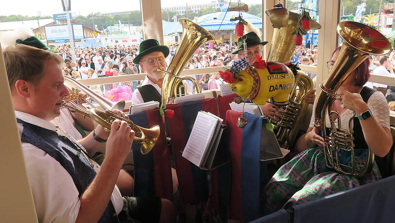 Das kleinste Blasorchester der Wiesn in seinem Musikantenbalkon – diesmal in der (Immer-)Fünfer-Besetzung von (v.l.) Robert, Christoph, Wiggerl, Thomas und Michaela. Fahrgäste, denen’s gefallen hat, werfen ein bisserl was ins gelbe Sparschwein.