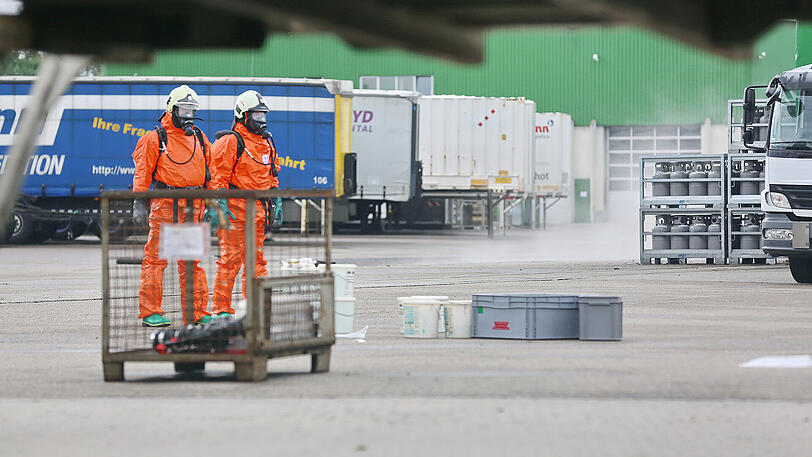Einsatzkräfte der Feuerwehr stehen am Montag auf einem Betriebsgelände in Neu-Ulm neben aufsteigenden Chlorgasen.