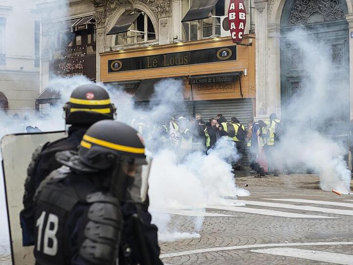 Polizisten feuern mit Tränengas auf "Gelbwesten"-Demonstranten nahe der Kirche "La Madeleine" in Paris. Erneut sind in Frankreich zahlreiche Menschen auf die Straße gegangen.