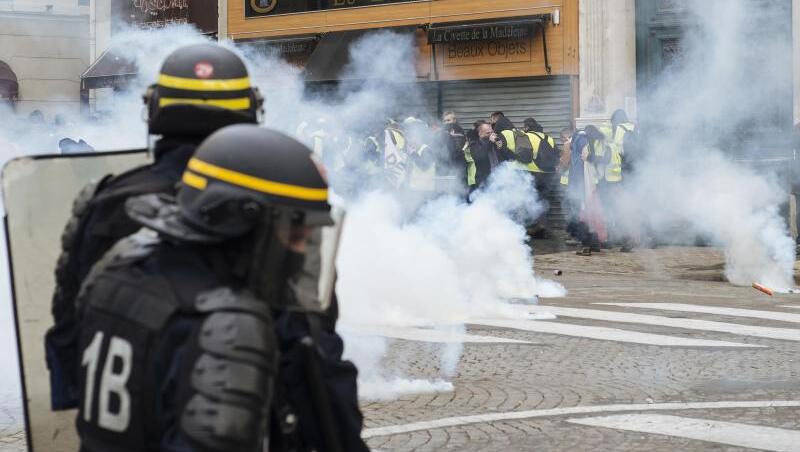 Polizisten feuern mit Tränengas auf "Gelbwesten"-Demonstranten nahe der Kirche "La Madeleine" in Paris. Erneut sind in Frankreich zahlreiche Menschen auf die Straße gegangen.
