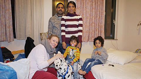 Die Familie mit ihrer Unterstützerin im kleinen Gasthauszimmer: Vater Sathiyappiraba Sathiyanathan und seine Frau Tharani (hinten), Nachbarin Petra Poppe, die kleine Yaahari (2) auf dem Schaukelpferd und Sohn Parujan (4).