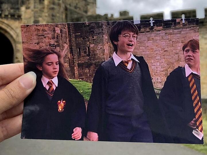 Die Filmtouristin Andrea David hält ein Foto aus dem Film "Harry Potter" in die Kamera.