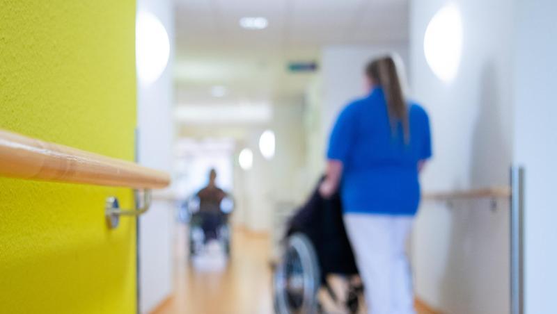 Eine Pflegerin schiebt eine Bewohnerin eines Pflegeheims in einem Rollstuhl über den Flur. Foto: Tom Weller/dpa/Archivbild Eine Pflegerin schiebt eine Bewohnerin eines Pflegeheims in einem Rollstuhl über den Flur. Foto: Tom Weller/dpa/Archivbild