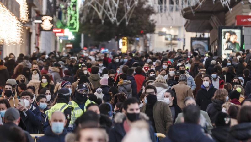 Zahlreiche Menschen mit Mund-Nasen-Schutz gehen eine Einkaufsstraße entlang.