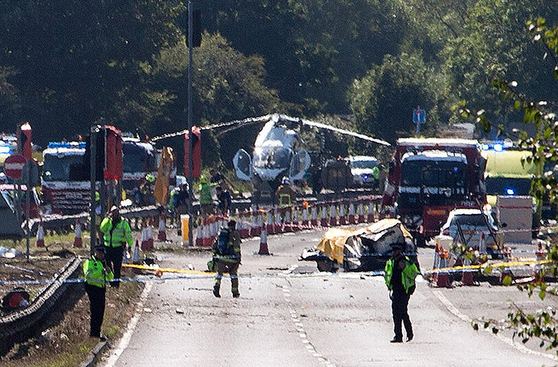 Katastrophe statt fröhlicher Flugshow: Polizisten und Rettungskräfte nähern sich der Absturzstelle auf einer stark befahrenen Straße.