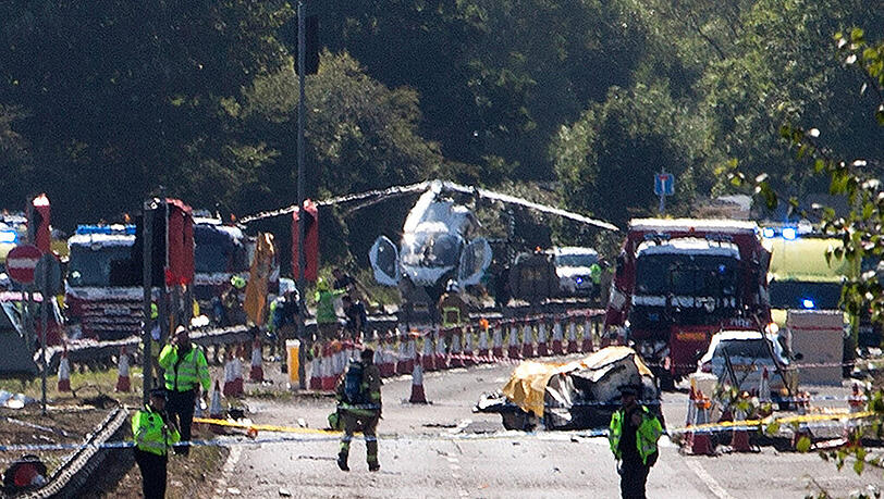 Katastrophe statt fröhlicher Flugshow: Polizisten und Rettungskräfte nähern sich der Absturzstelle auf einer stark befahrenen Straße. Katastrophe statt fröhlicher Flugshow: Polizisten und Rettungskräfte nähern sich der Absturzstelle auf einer stark befahrenen Straße.