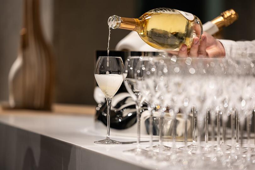 Ein Kellner schenkt ein Glas Champagner ein.