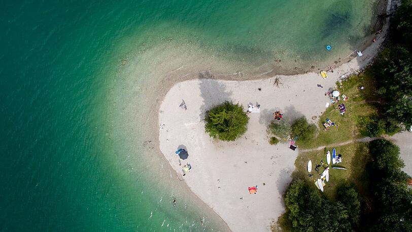 Menschen genießen die Sonne am Walchensee-Südufer.