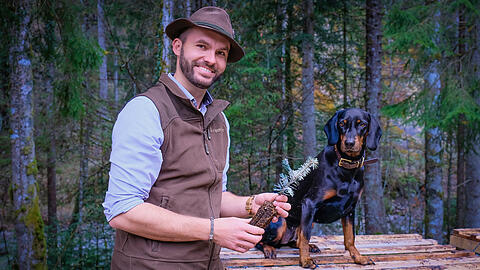 F&ouml;rster Philip M&uuml;ller (32) leitet das Revier Jachenau der Bayerischen Staatsforsten. Neben ihm sitzt seine aufgeweckte H&uuml;ndin Xena. In der Hand h&auml;lt er eine kleine Tanne f&uuml;r die Fr&uuml;hjahrsbepflanzung. Bespr&uuml;ht ist sie mit Schafsfett und Sand zum Schutz vor Rehen.