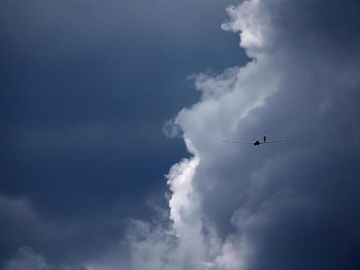 Ein vor den Wolken fliegendes Segelflugzeug wird von der Sonne beschienen. Foto: Karl-Josef Hildenbrand/dpa/Archivbild