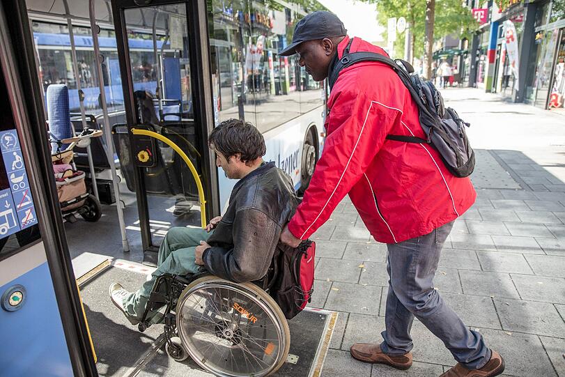 Gut erkennbar in roten Jacken unterstützen ab Montag Mobilitätshelfer Menschen mit Behinderung bei ihrem Weg durch die Stadt.