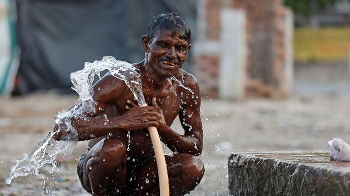 Ein Mann badet an einem &ouml;ffentlichen Wasserhahn in der N&auml;he des Ganges in Prayagraj w&auml;hrend eines hei&szlig;en Sommertages.